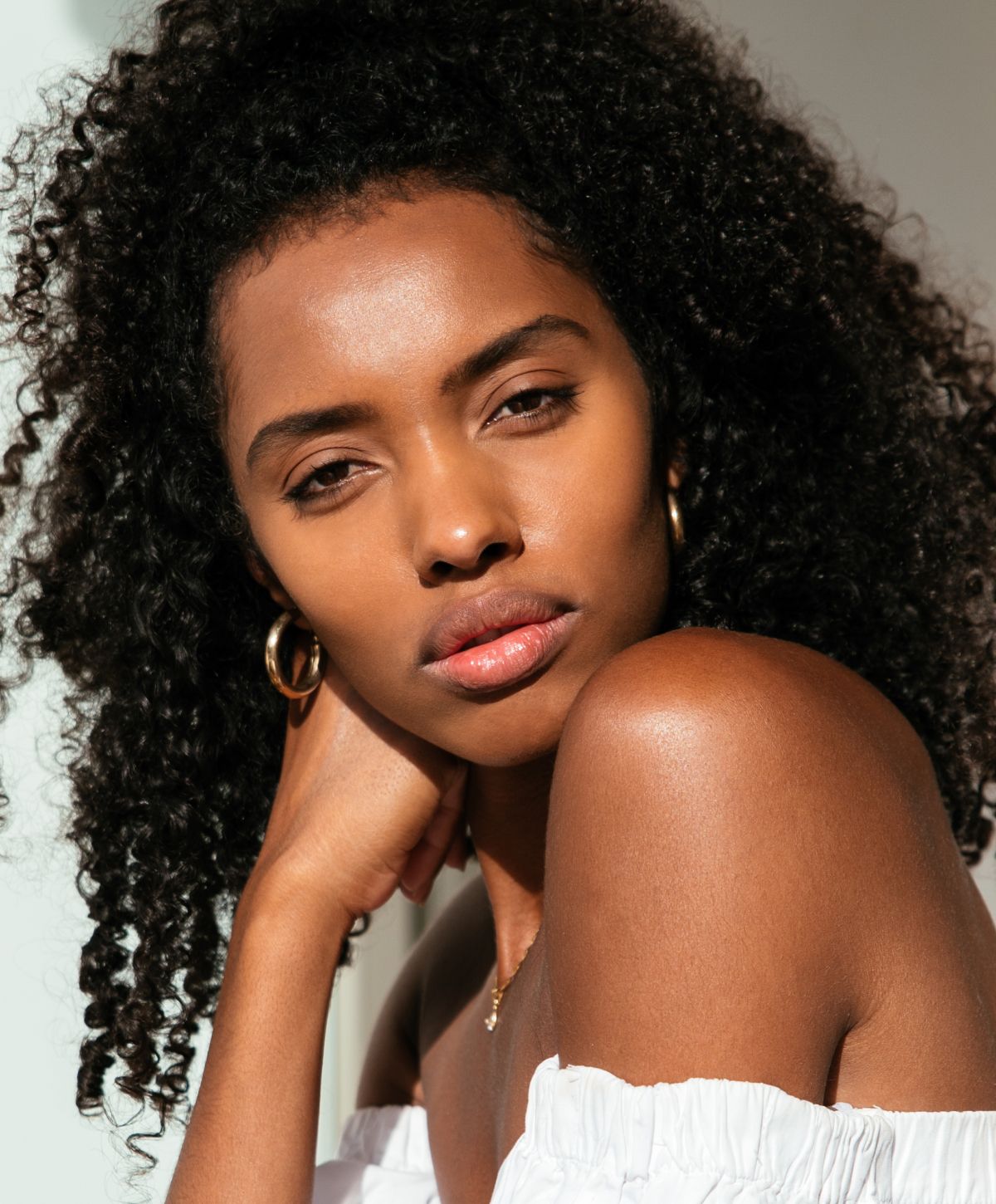 Orange County Botox model with curly hair, wearing off-shoulder top.