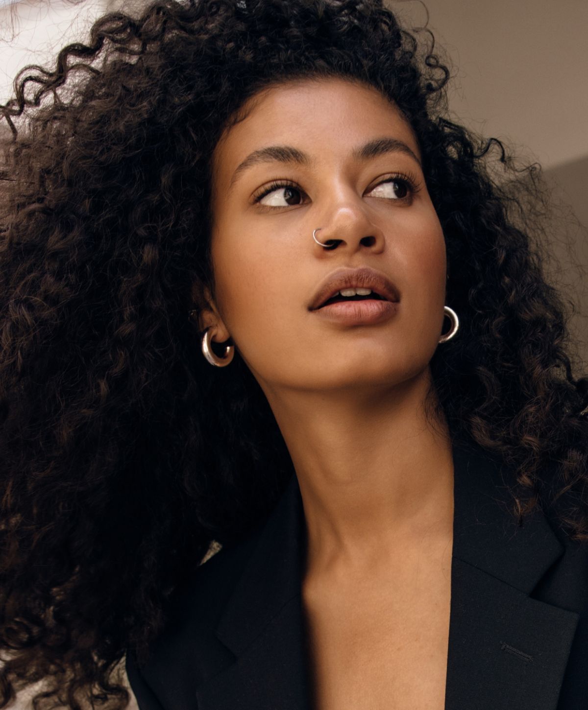 Orange County lip filler model with curly hair wearing earrings and blazer.
