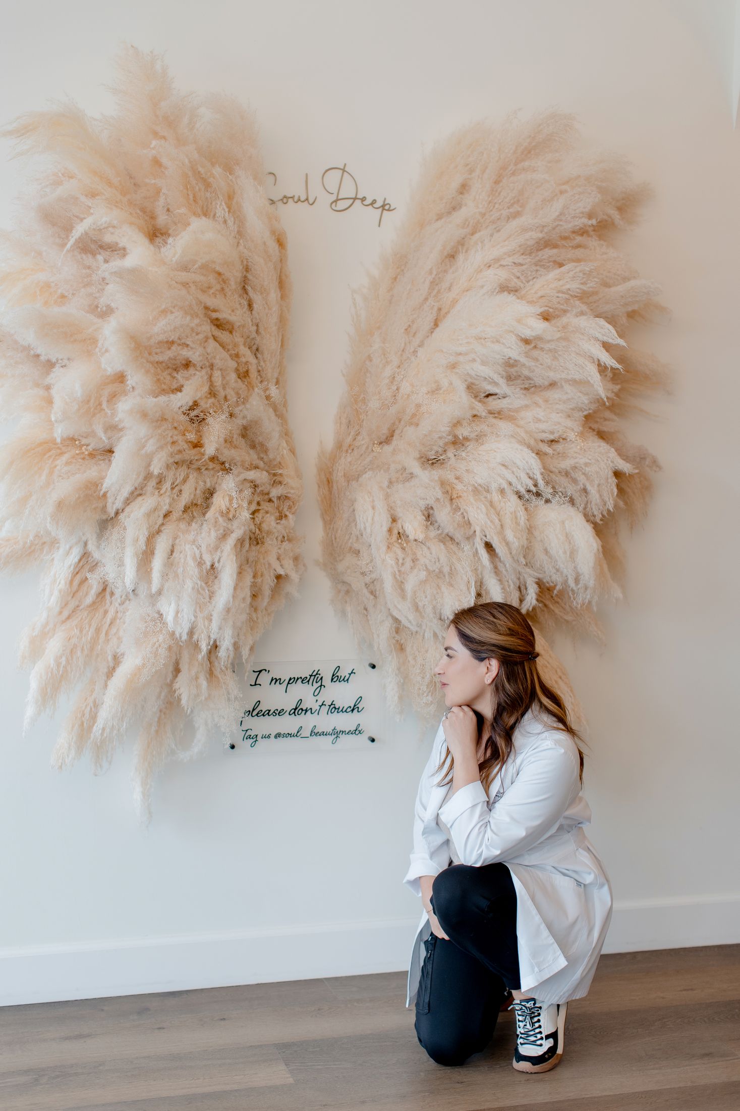 Woman admiring decorative wings on wall.