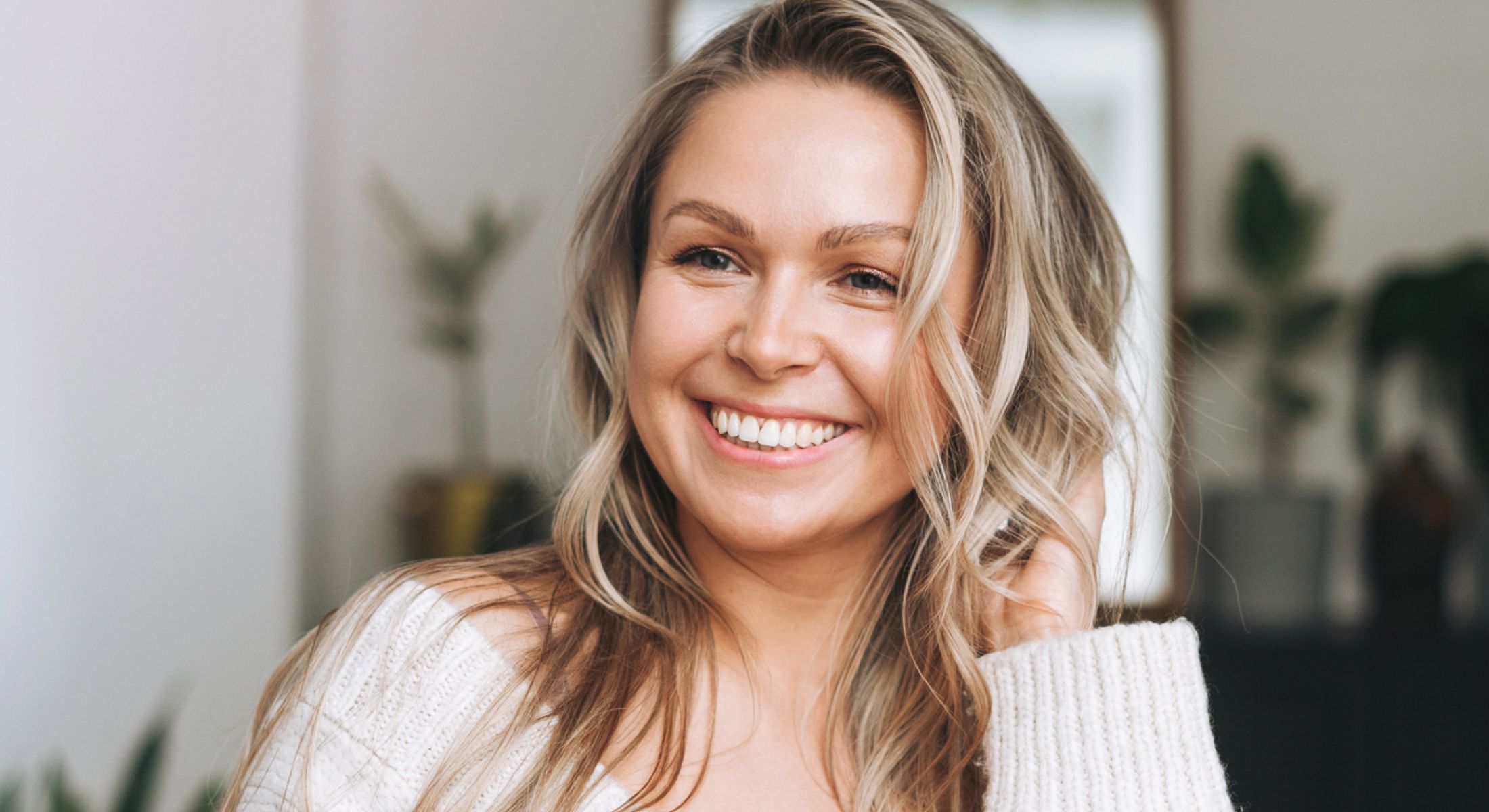 Smiling woman with long, wavy blonde hair.