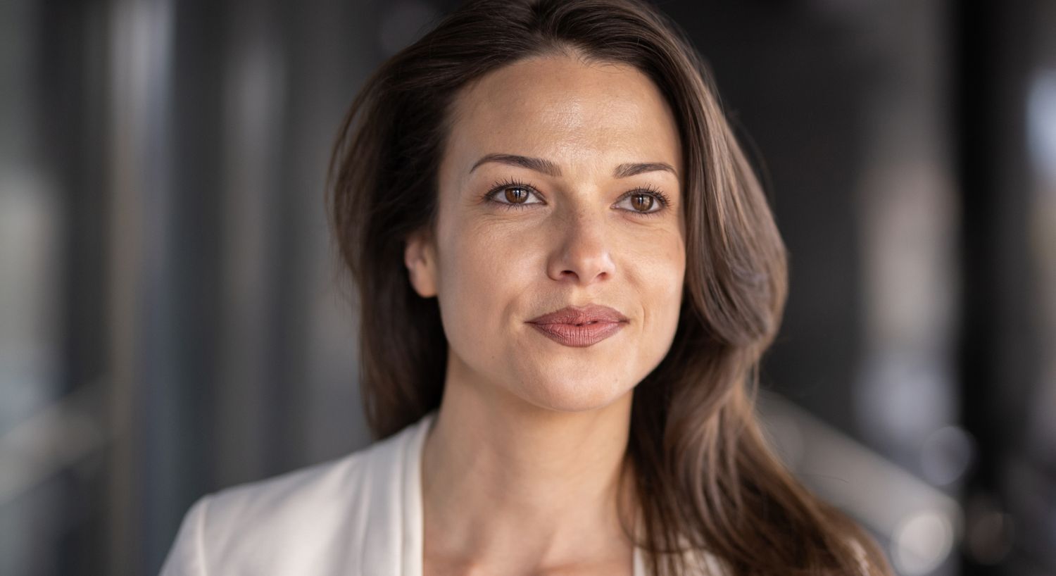 Confident Orange County SKINVIVE model with long hair in soft lighting.