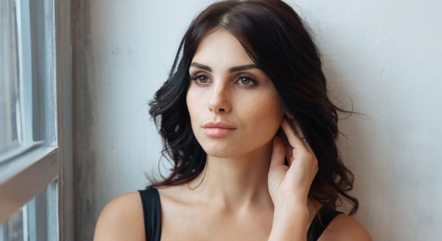 Orange County Radiesse model with long hair looking thoughtfully out window