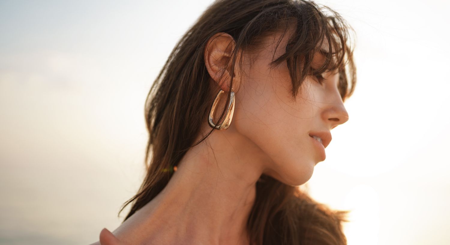 Orange County chemical peel model wearing elegant earrings by the seaside.